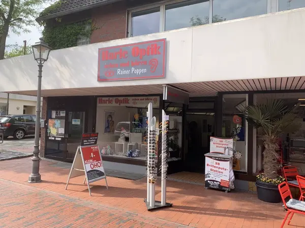 Das Bild zeigt das Geschäft Harle Optik mit Brillenständern und Brillenputzstation vor dem Laden.