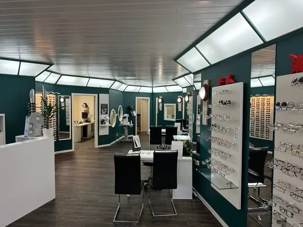 Modernes Optikerfachgeschäft mit Brillenregalen, Beratungstischen und stilvoller Beleuchtung.