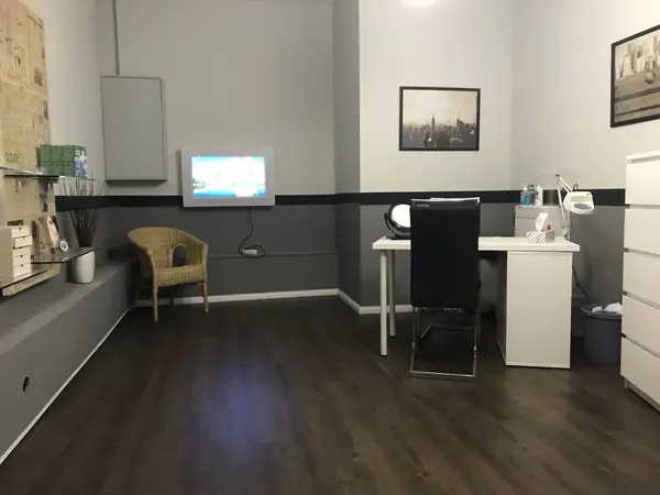 Modern eingerichtetes Kosmetikstudio mit Behandlungstisch, Stuhl und Dekoration.